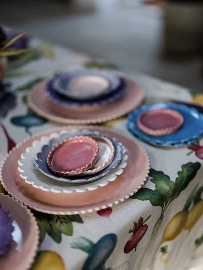 stacks of scalloped edge tableware with pink coasters